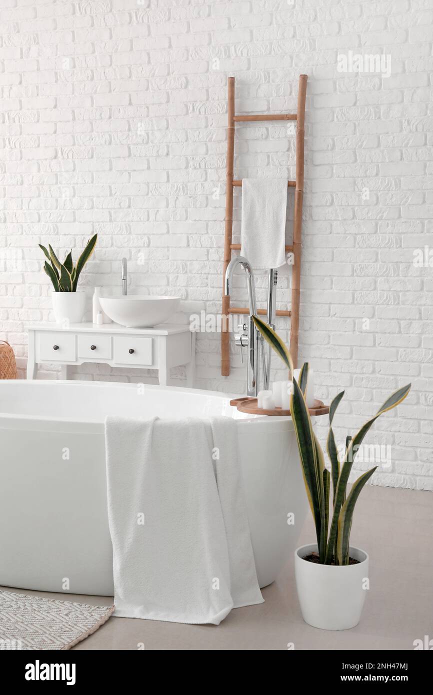 Interior of light bathroom with bathtub, sink and ladder Stock Photo