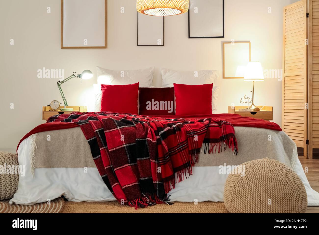 Interior of bedroom with red checkered blankets on bed, blank frames