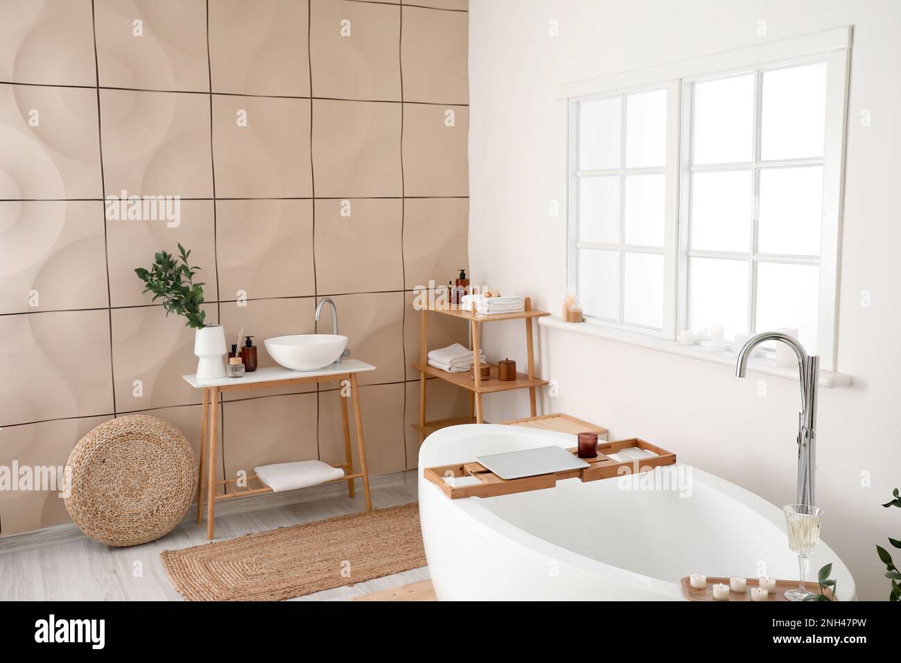 Interior of bathroom with modern bathtub, laptop, champagne and burning