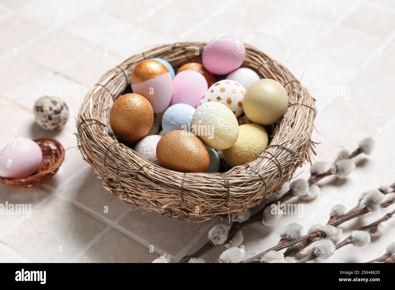 Nest with Easter eggs and willow branches on light tile Stock Photo - Alamy