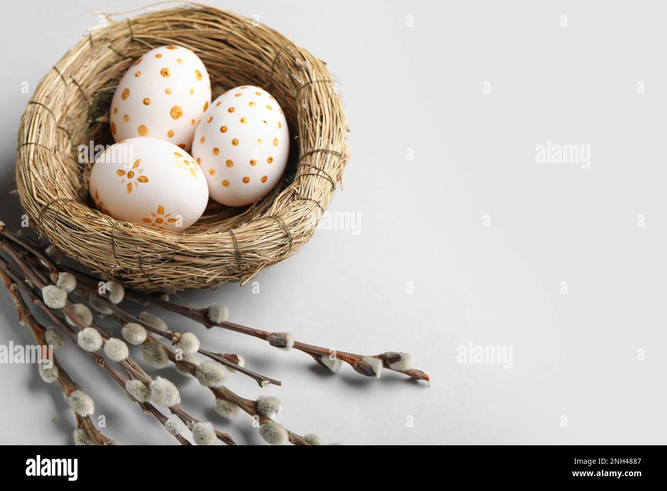 Nest with painted Easter eggs and willow branches on light background ...