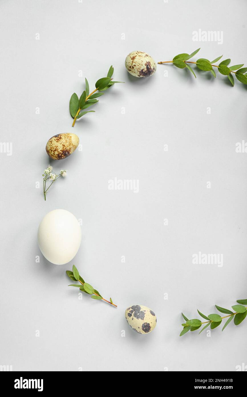 Frame made of Easter eggs and eucalyptus branches on grey background Stock Photo