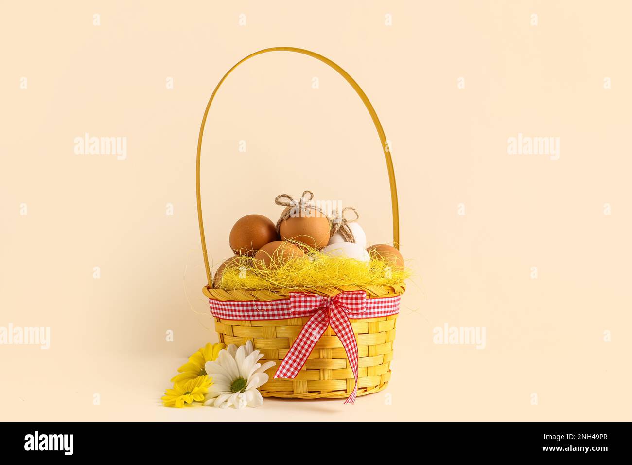 Wicker basket with Easter eggs and chrysanthemum flowers on white ...