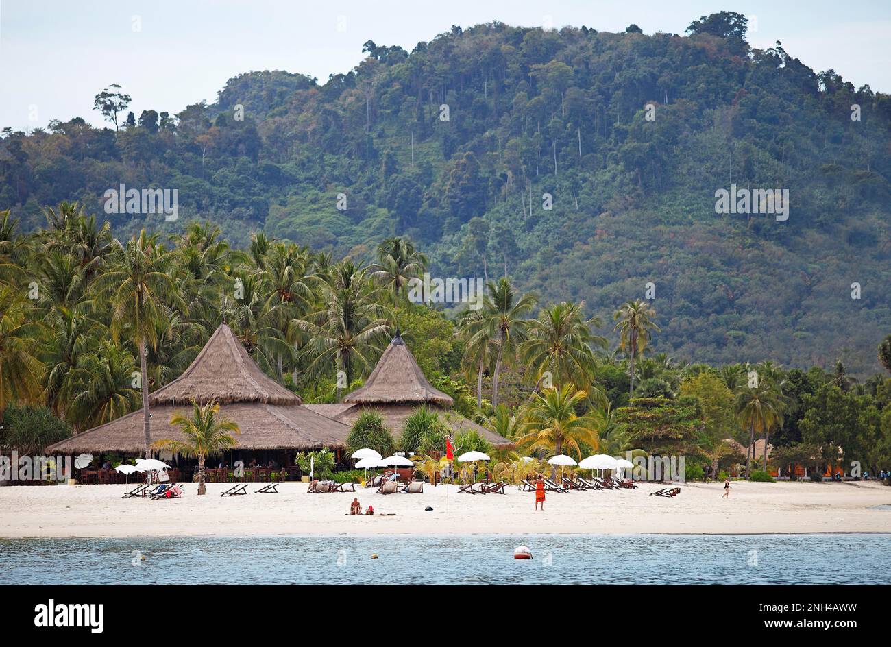 Sandy beach beach and straw huts at Sivalai Resort, green local mountain in the back, Koh Mook, Andaman Sea, Southern Thailand, Thailand Stock Photo