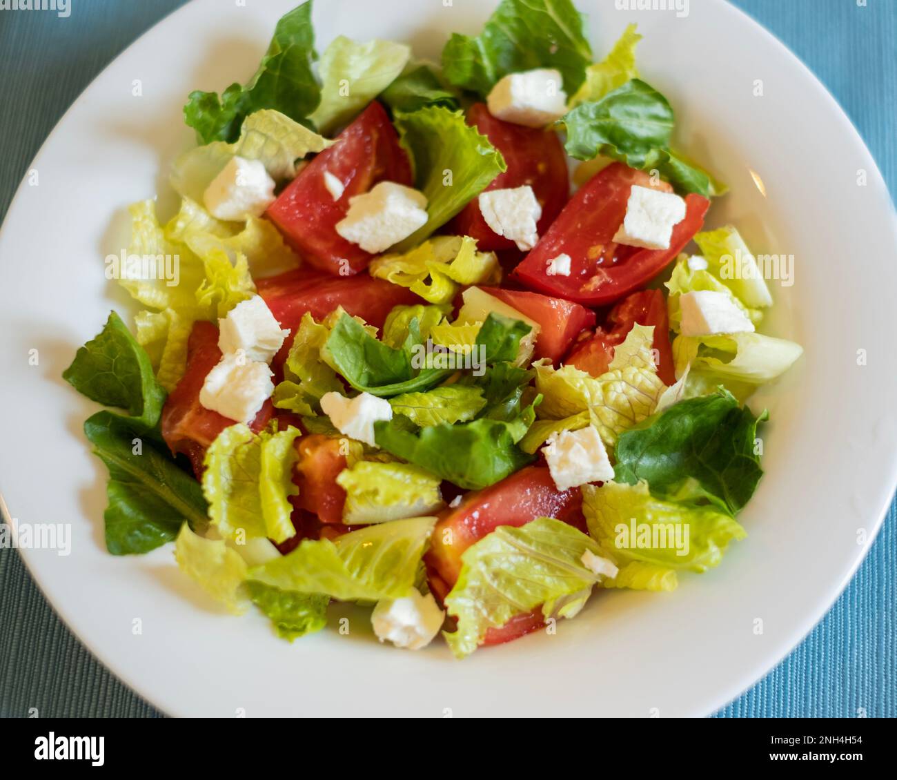 A fresh salad with romaine lettuce, cut tomatoes & feta cheese in a