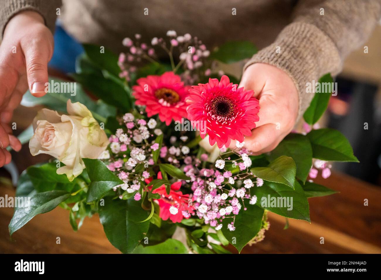 Female florist is putting beautiful spring flowers together in a vase