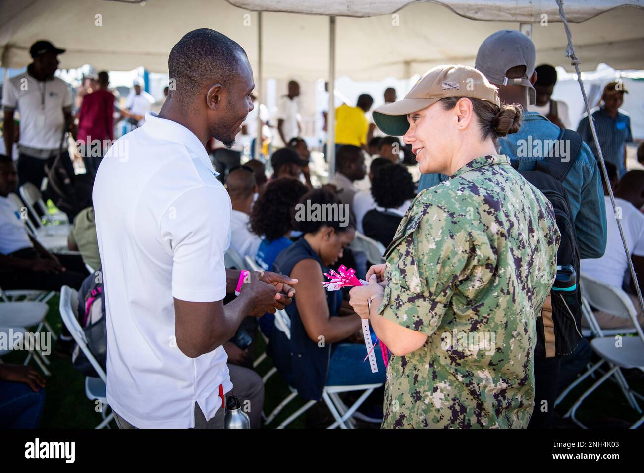 Lt. Cmdr. Anna Achlenker, a clinical nurse specialist assigned to the hospital ship USNS Comfort (T-AH 20), passes out translator wristbands at the medical site in Jeremie, Haiti, during Continuing Promise 2022, Dec. 12, 2022. Comfort is deployed to U.S. 4th Fleet in support of CP22, a humanitarian assistance and goodwill mission conducting direct medical care, expeditionary veterinary care, and subject matter expert exchanges with five partner nations in the Caribbean, Central and South America. Stock Photo