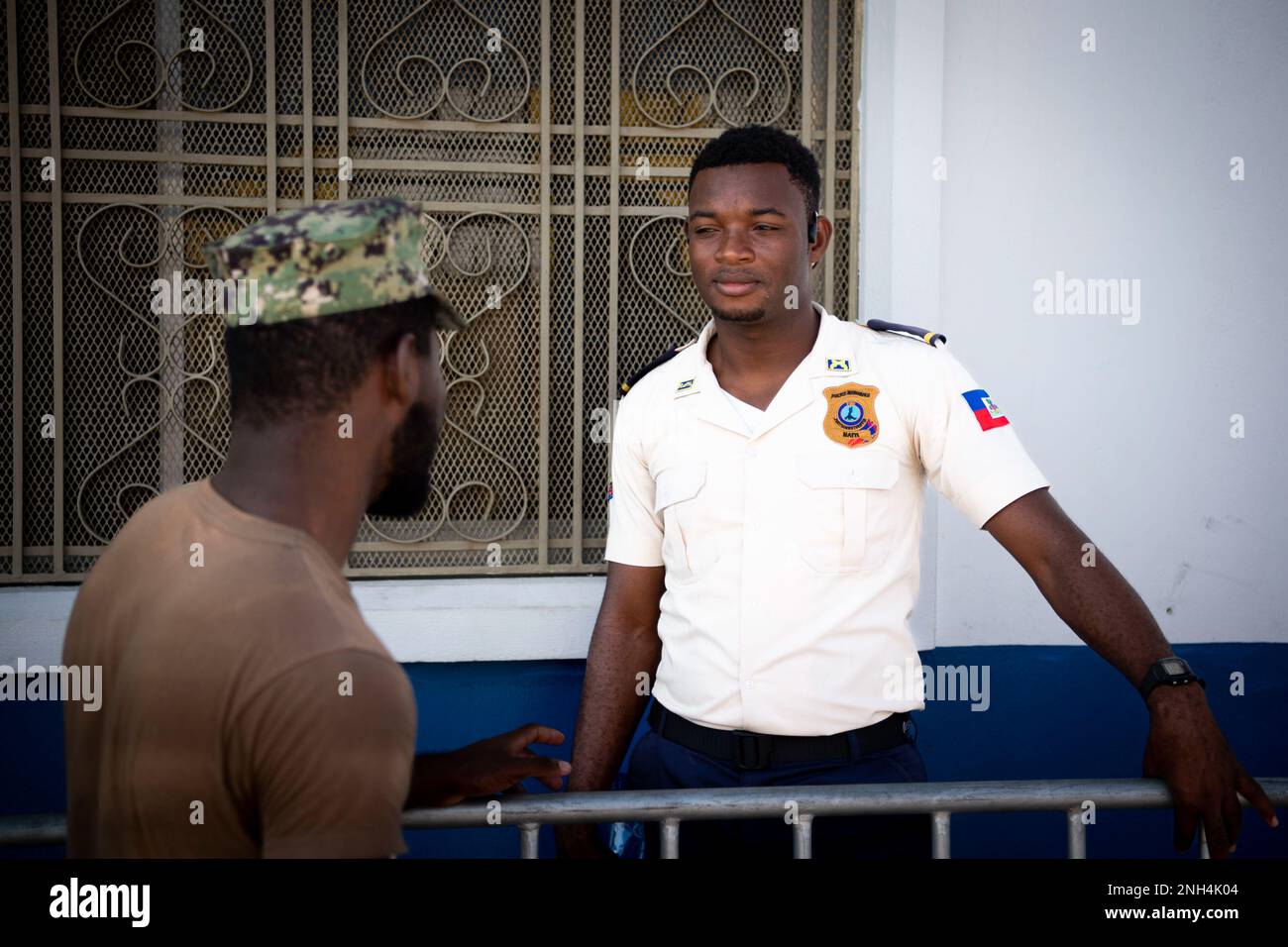 Seaman Paul Wedely, left, from Cap-Haitian, Haiti, assigned to the hospital ship USNS Comfort (T-AH 20), speaks with a local Haitian police officer assisting with patient intake at the medical site in Jeremie, Haiti, during Continuing Promise 2022, Dec. 12, 2022. Comfort is deployed to U.S. 4th Fleet in support of CP22, a humanitarian assistance and goodwill mission conducting direct medical care, expeditionary veterinary care, and subject matter expert exchanges with five partner nations in the Caribbean, Central and South America. Stock Photo
