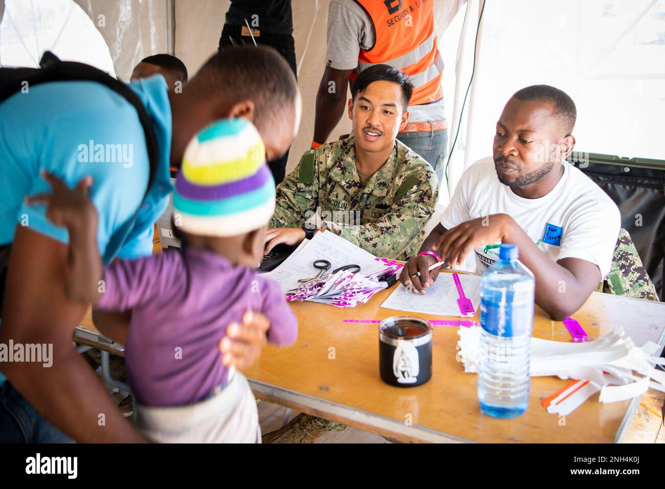 Hospital Corpsman First Class Aldrin Elgincolin, from Union City, California, assigned to the hospital ship USNS Comfort (T-AH 20), and Jean Daniel Pierre, a translator from Jeremie, Haiti check-in patients at the medical site in Jeremie, Haiti, during Continuing Promise 2022, Dec. 12, 2022. Comfort is deployed to U.S. 4th Fleet in support of CP22, a humanitarian assistance and goodwill mission conducting direct medical care, expeditionary veterinary care, and subject matter expert exchanges with five partner nations in the Caribbean, Central and South America. Stock Photo