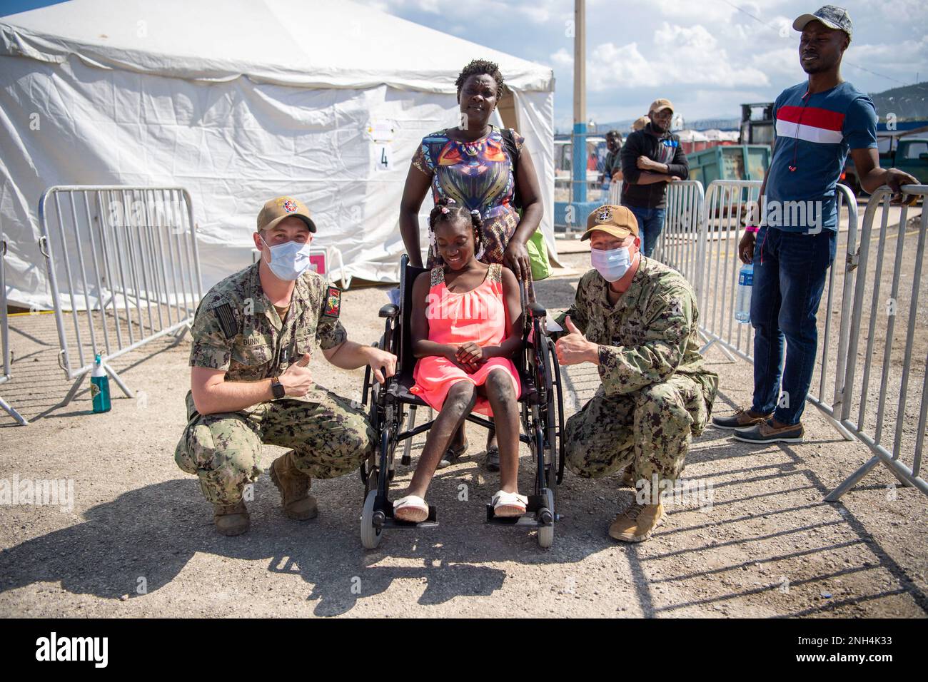 Capt. Michael Weaver, right, ground force commander for Continuing Promise 2022 in Haiti, and Lt. j.g. Blake Dunn, an intensive care unit nurse from Atlanta, Georgia, assigned to the hospital ship USNS Comfort (T-AH 20), give a wheelchair to a young Haitian after providing care at a medical site in Jeremie, Haiti, Dec. 12, 2022. Comfort is deployed to U.S. 4th Fleet in support of CP22, a humanitarian assistance and goodwill mission conducting direct medical care, expeditionary veterinary care, and subject matter expert exchanges with five partner nations in the Caribbean, Central and South Ame Stock Photo