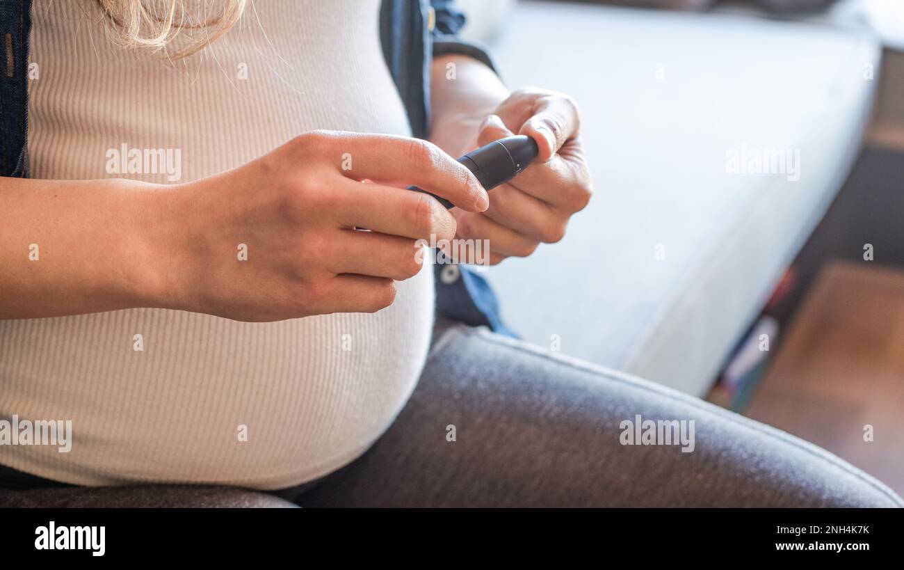 Close-up Of Pregnant Woman using lancing device for blood glucose monitoring Stock Photo