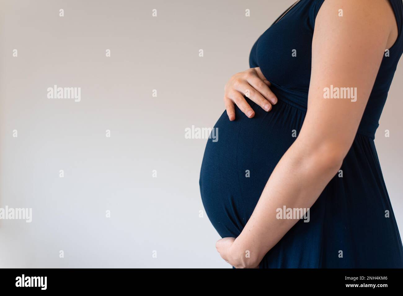 Pregnant woman wearing blue dress holding her belly Stock Photo - Alamy