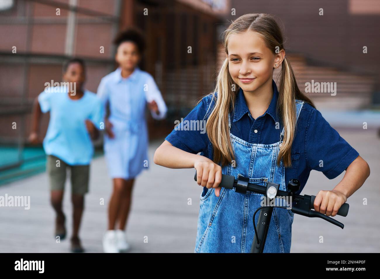 Students Running Riding Blond pretty schoolgirl with two ponytails riding electric scooter in ...