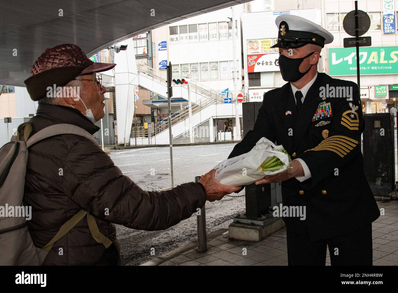 YOKOSUKA, Japan (Dec. 13, 2022) — Command Master Chief Robert Beachy, assigned to Commander, Fleet Activities Yokosuka (CFAY) hands out a Japanese daikon radish to a pedestrian at Yokosuka Chuo Station during an event raising awareness of drunk driving during the holiday season. “Daikon” is a play on words as it is close to the Japanese word “daikonzetsu”, meaning eradication (of drunk driving). For more than 75 years, CFAY has provided, maintained, and operated base facilities and services in support of the U.S. 7th Fleet’s forward deployed naval forces, tenant commands, and thousands of mili Stock Photo