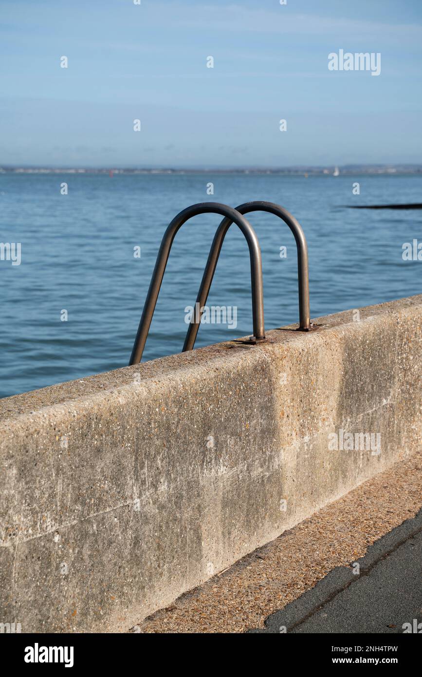 A metal handrail ladder guide leading to the sea on the waterfront in Cowes, Isle of Wight, on a sunny day. Stock Photo