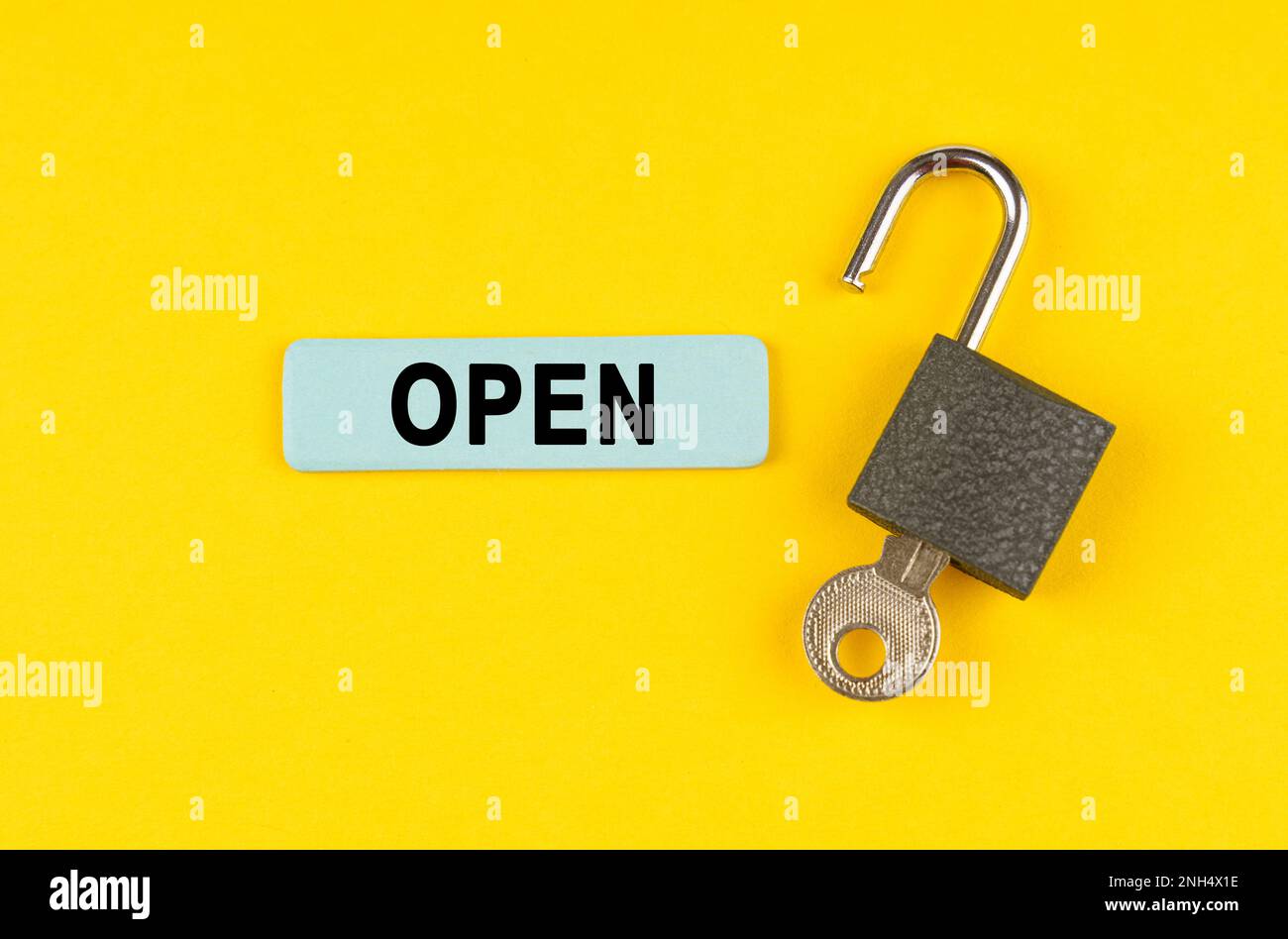 On the yellow surface lies an open lock with a key, next to it is a ...