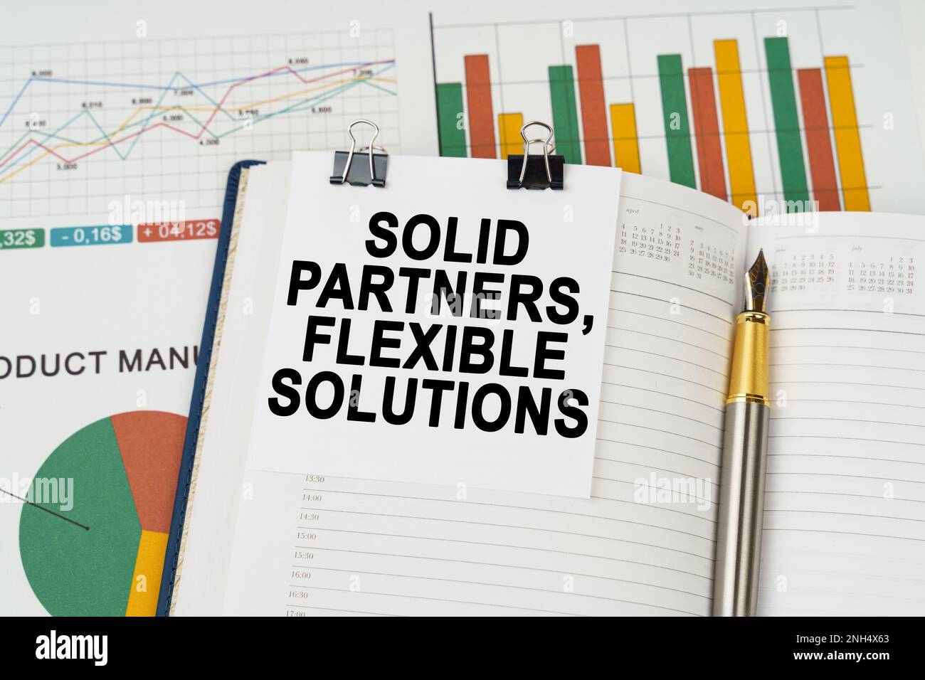 Business concept. On the business charts lies a pen, a notepad with note paper with the inscription - Solid partners, flexible solutions Stock Photo