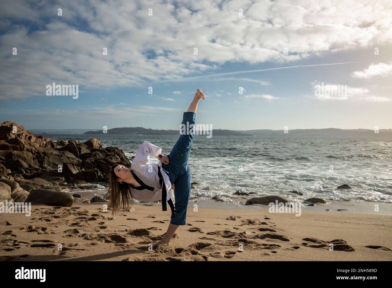 woman doing taekwondo on the beach giving a kick Stock Photo