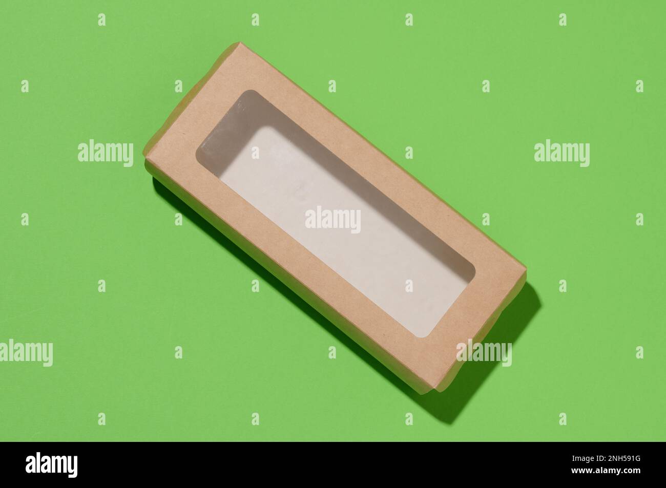 Rectangular cardboard box with a transparent plastic lid on a green background, top view Stock Photo