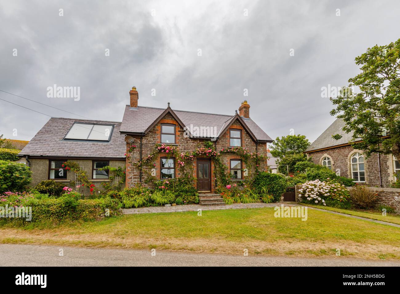 Large local style detached house with pink roses round the front door
