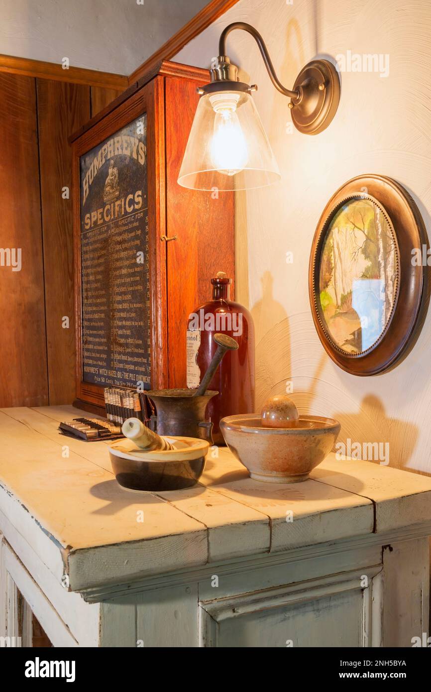 Pharmaceutical crusher bowls called Mortar and Pestle on top of antique wooden cabinet in upstairs master bedroom inside old 1841 cottage style home. Stock Photo