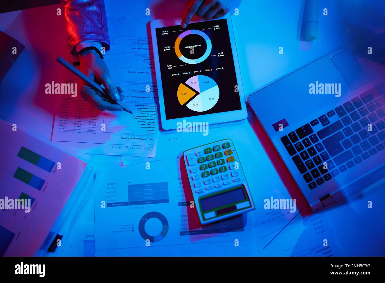 Upper view of modern woman with calculator, documents, laptop and tablet PC working with graphs. Stock Photo