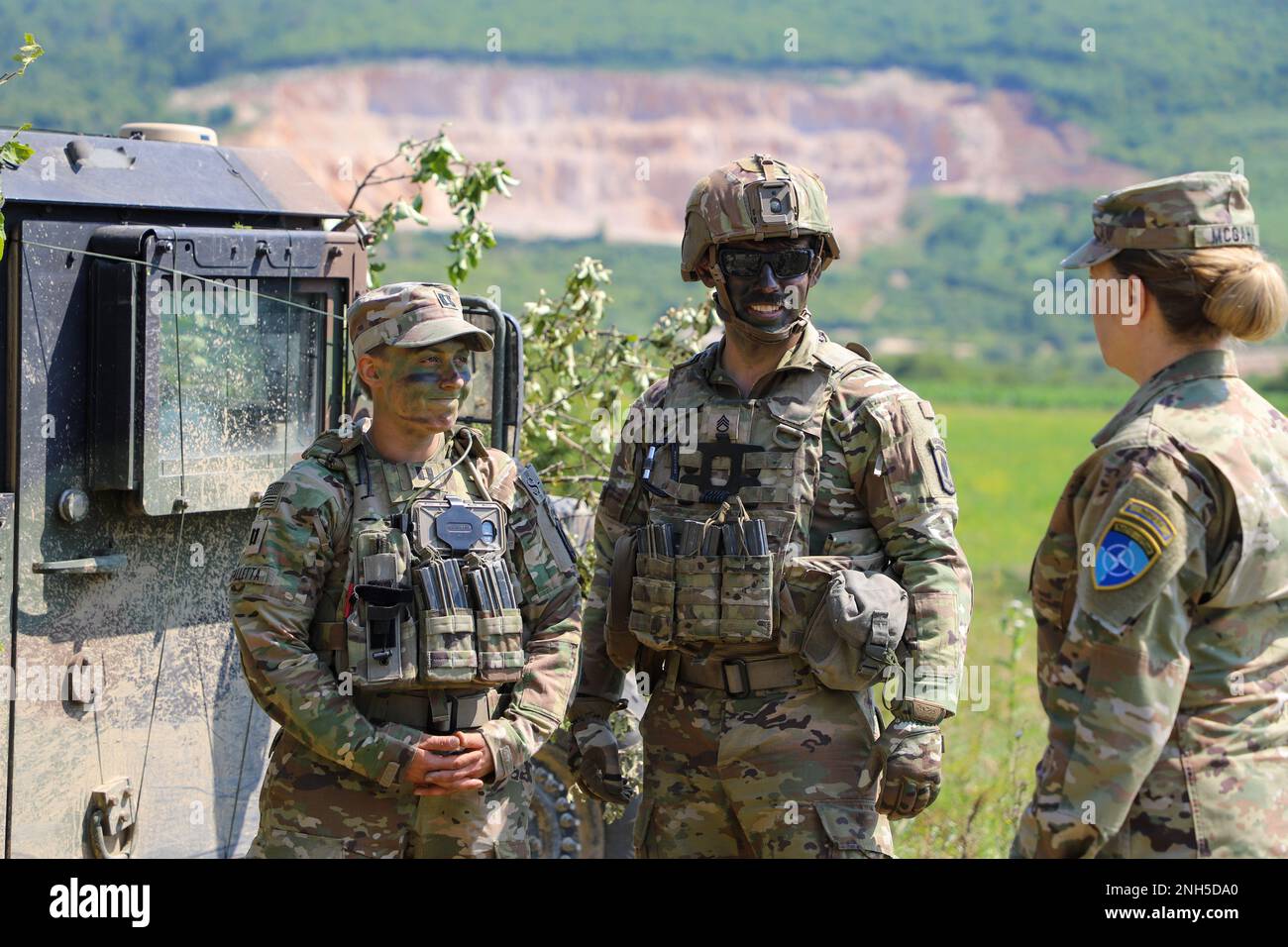 U.S. Army Capt. Charley Falletta (left), the commanding officer, and Staff Sergeant Zachary Stubbs, a fire support specialist, of the 1st Squadron, 91st Cavalry Regiment, 173rd Airborne Brigade and Brig. Gen. Pamela L. McGaha (left), Commander of NATO HQ Sarajevo, discuss training plans at Kasarna Manjaca, Dobrnja, Bosnia-Herzegovina on July 17, 2022. Guard members assigned to the State Medical Detachment and 1-169th Aviation Regiment, Maryland Army National Guard, trained alongside active duty Soldiers from the 1st Squadron, 91st Cavalry Regiment, 173rd Airborne Brigade, 12th Combat Aviation Stock Photo