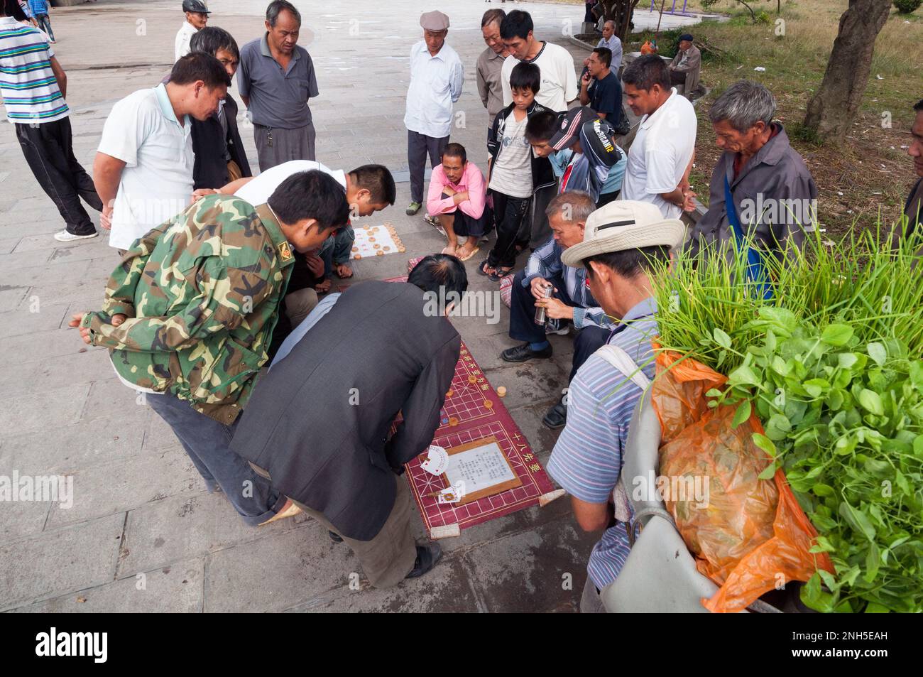 A group of men gathered to watch a a game of Chinese chess in an old town street in the city of Jianshui, Yunnan province China Stock Photo
