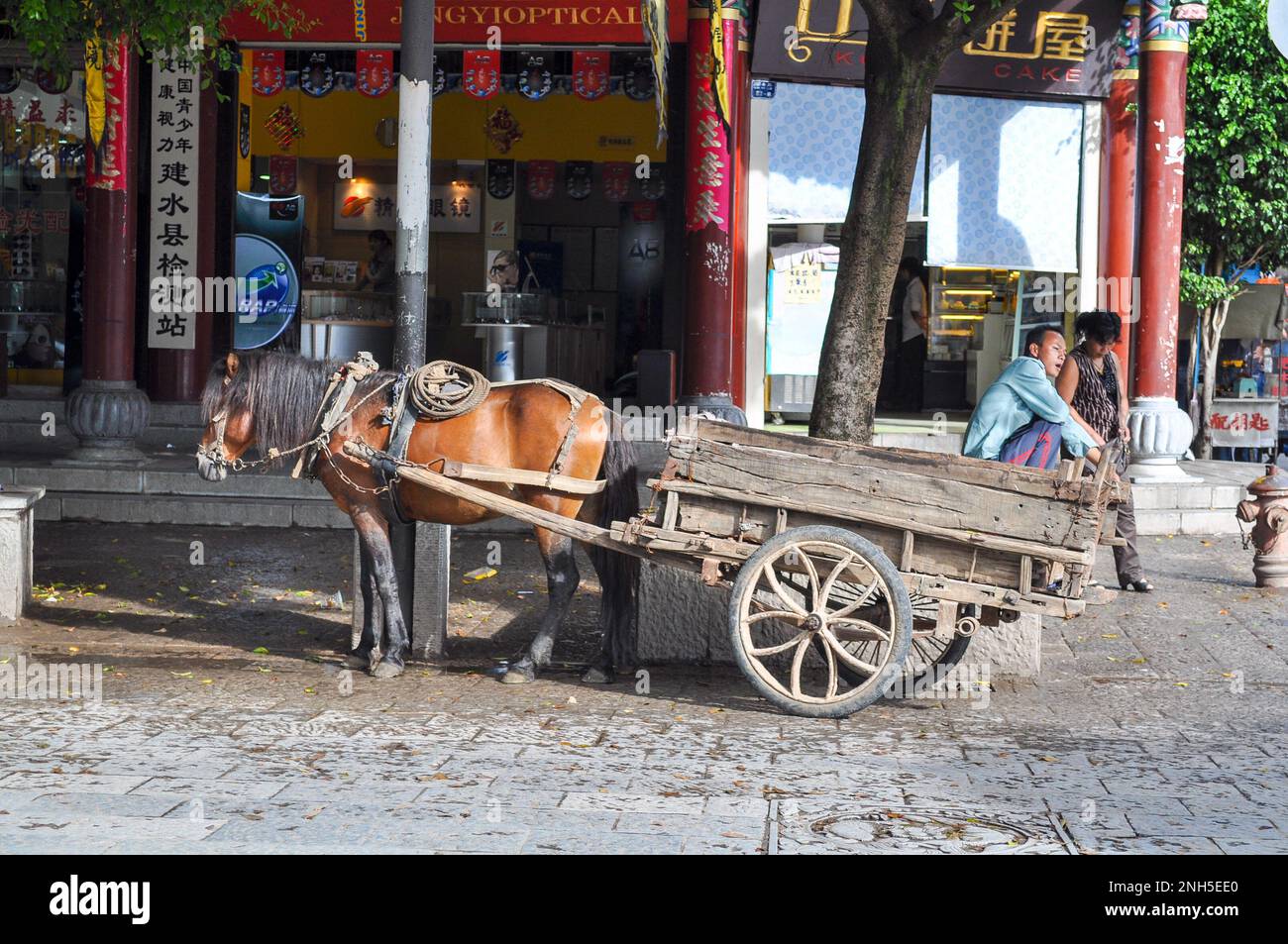 A rural man sitting with his horse and cart in old town of JIanshui Yunnan Province China Stock Photo