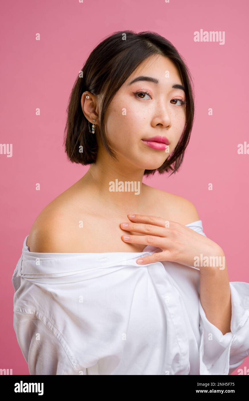 Close up of young asian woman with short in white blouse on pink background | makeup | fashion Stock Photo