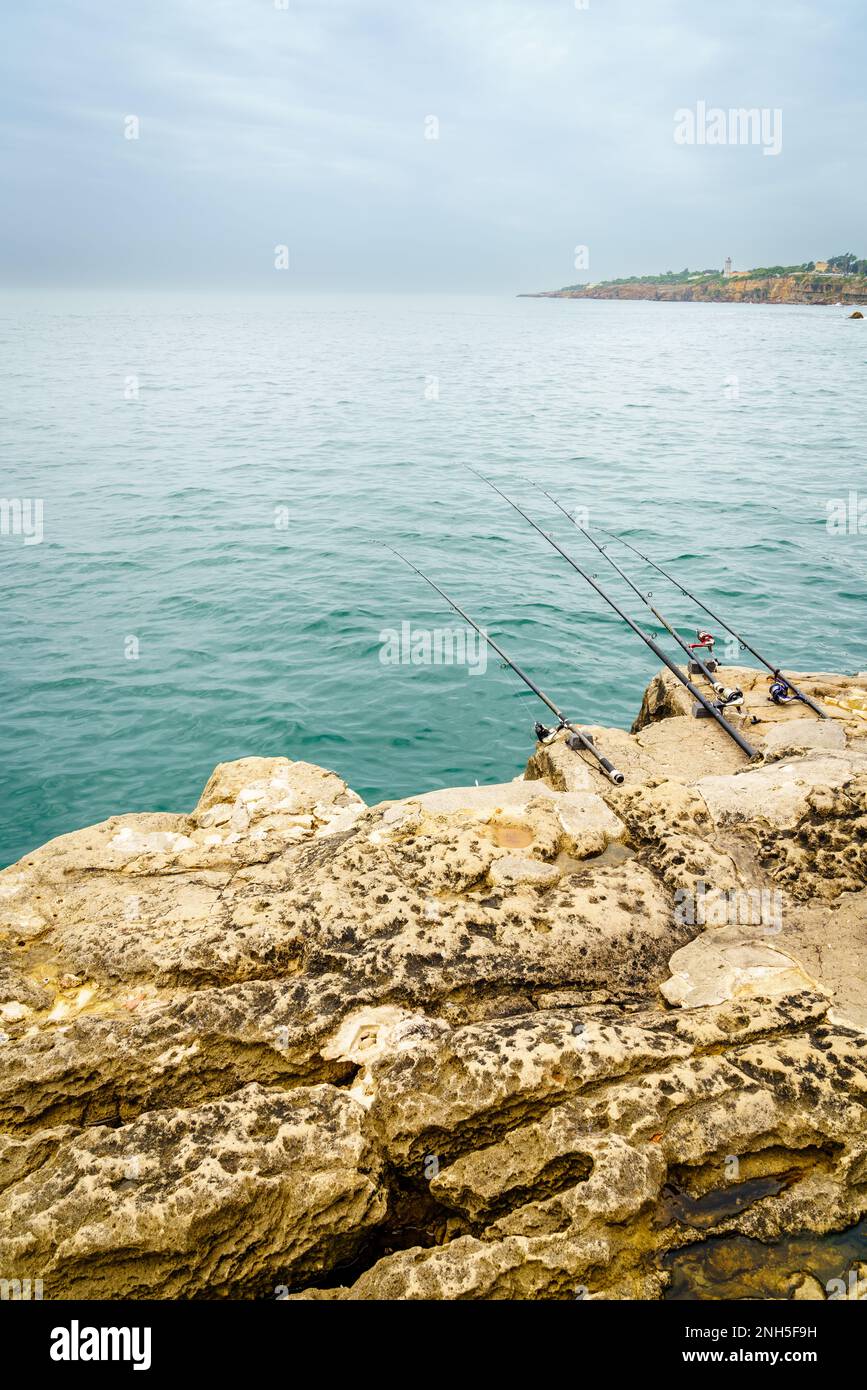 Fishing rods on the rocks of the coast of Cascais, Portugal Stock Photo
