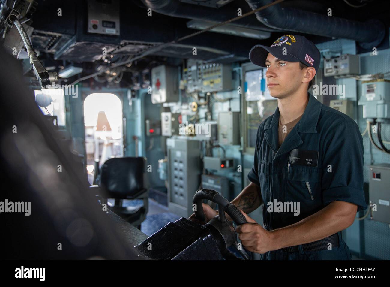 220717-N-QI593-2106 MEDITERRANEAN SEA (July 17, 2022) Seaman Robert Tejkl, from Mansfield, Texas, steers the Arleigh Burke-class guided missile destroyer USS Bainbridge (DDG 96) from the ship’s pilot house in the Mediterranean Sea, July 17, 2022. Bainbridge is on a scheduled deployment in the U.S. Naval Forces Europe area of operations, employed by U.S. Sixth Fleet to defend U.S., allied and partner interests. Stock Photo