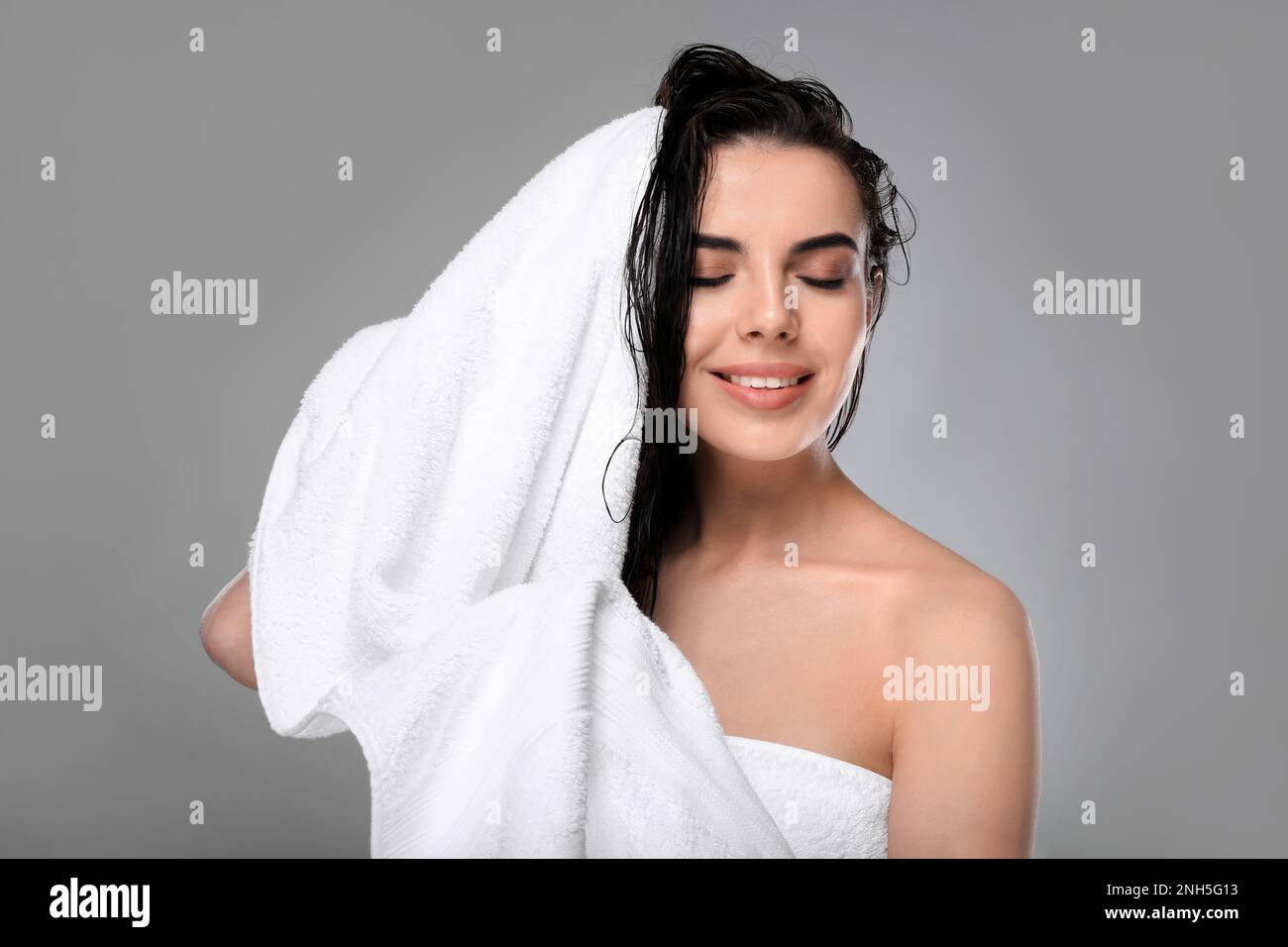Happy young woman drying hair with towel after washing on light grey background Stock Photo Alamy
