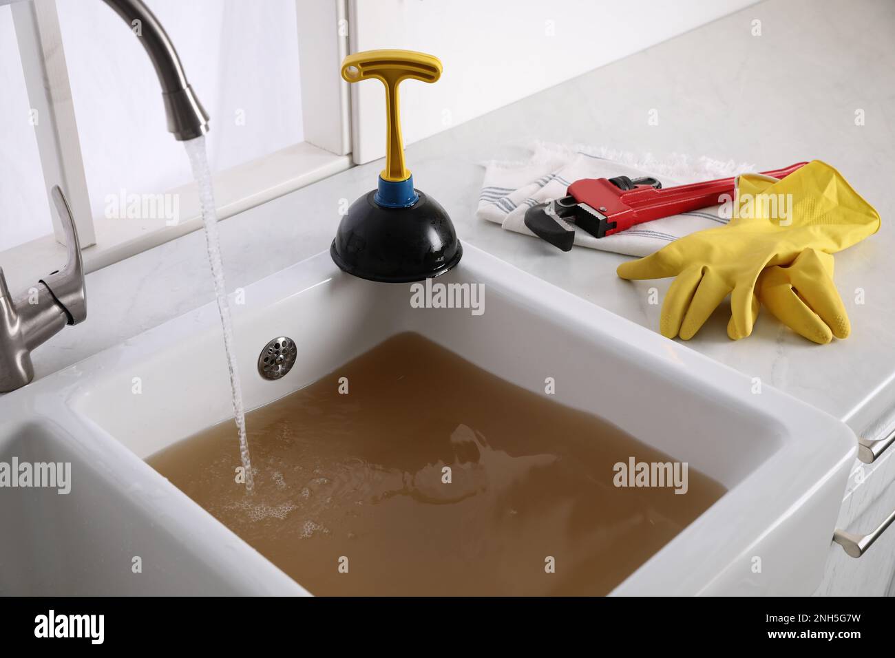 Kitchen counter with clogged sink, plunger and plumber's accessories Stock Photo Alamy