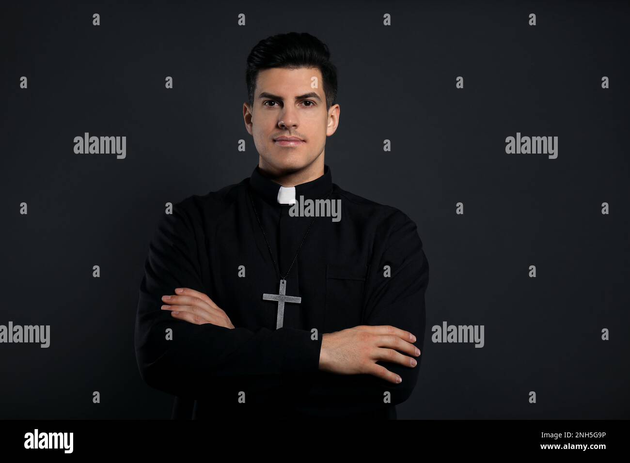 Priest in cassock with cross on black background Stock Photo