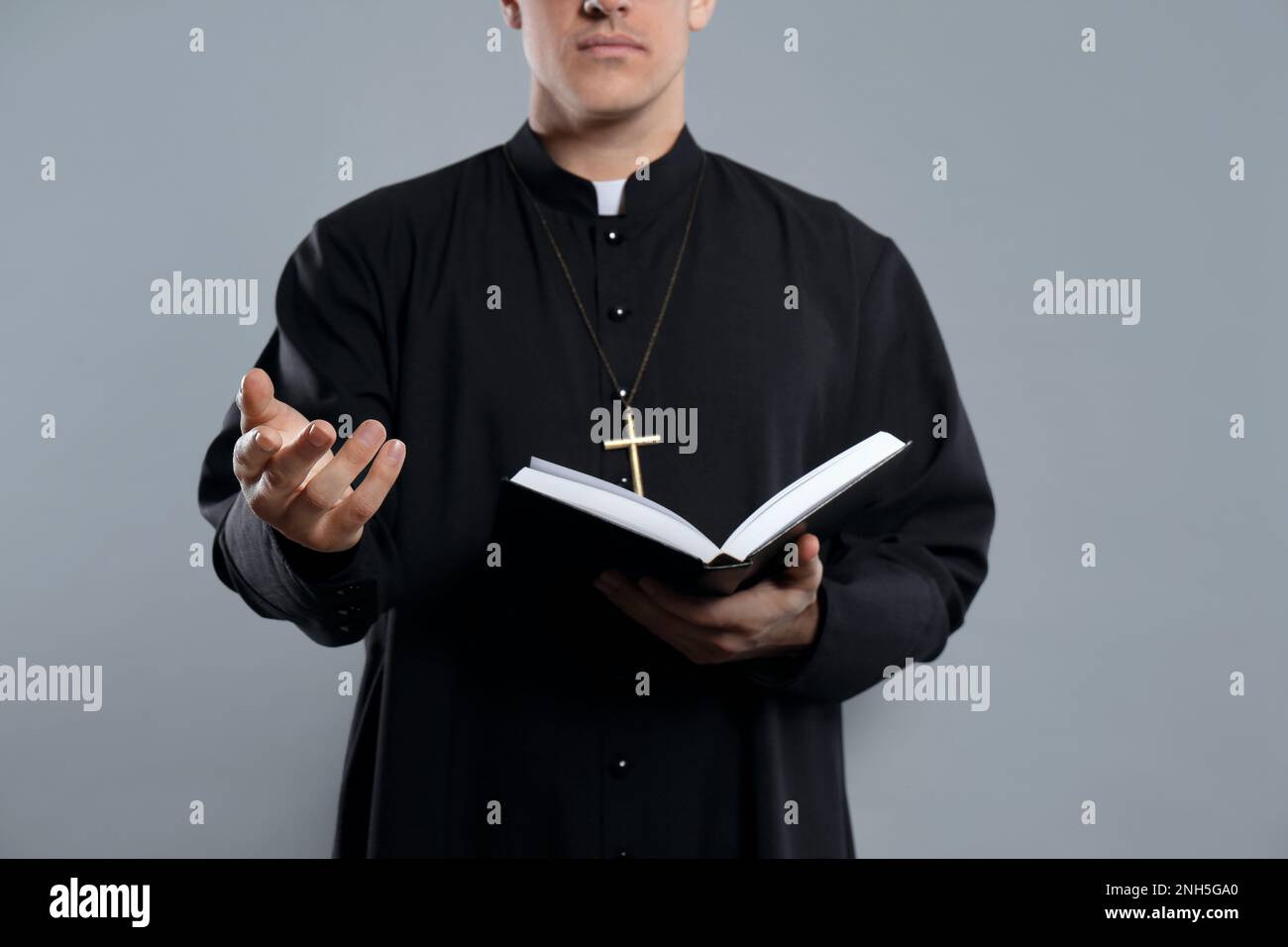 Priest with Bible on grey background, closeup Stock Photo