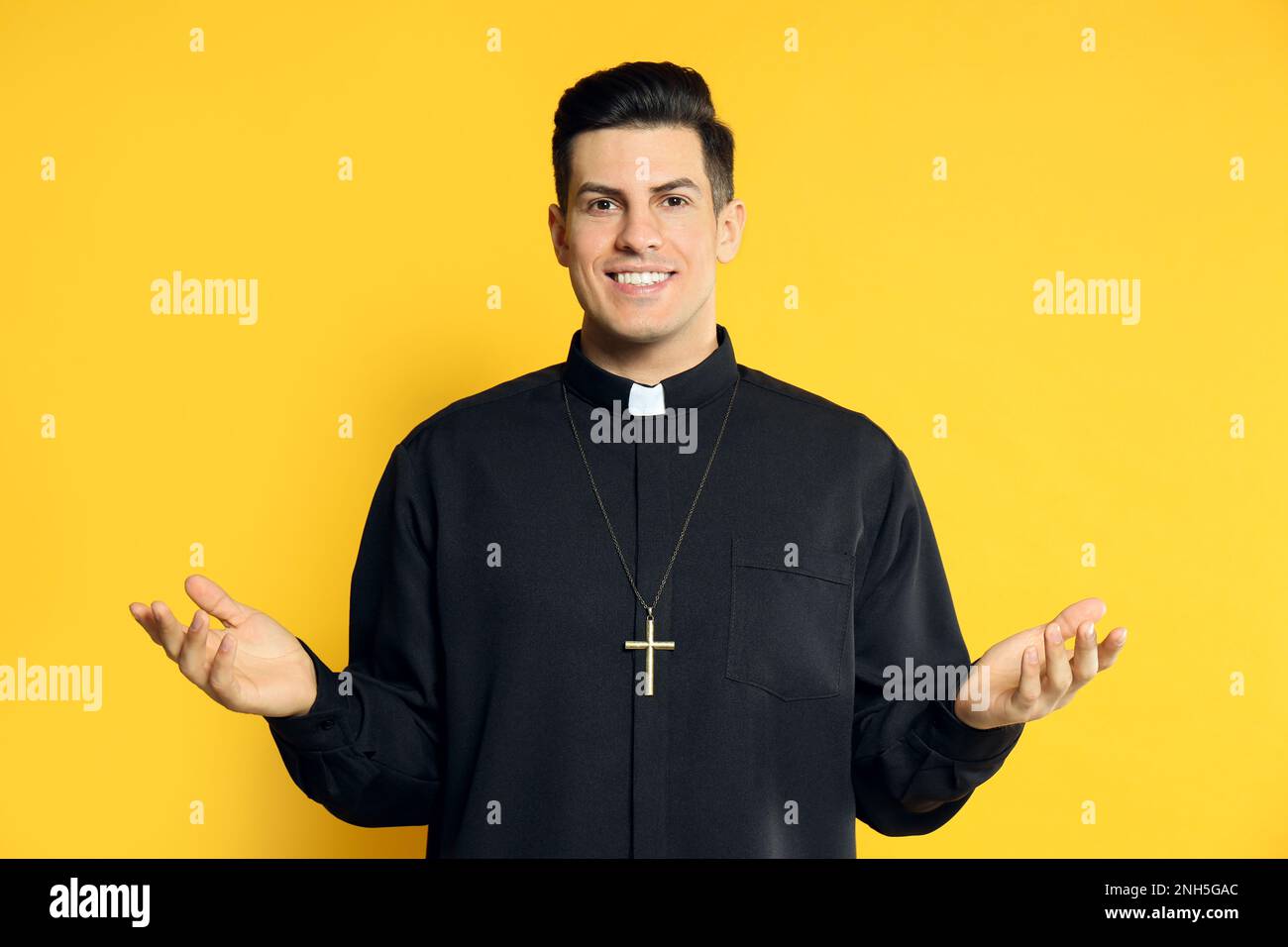 Priest wearing cassock with clerical collar on yellow background Stock Photo