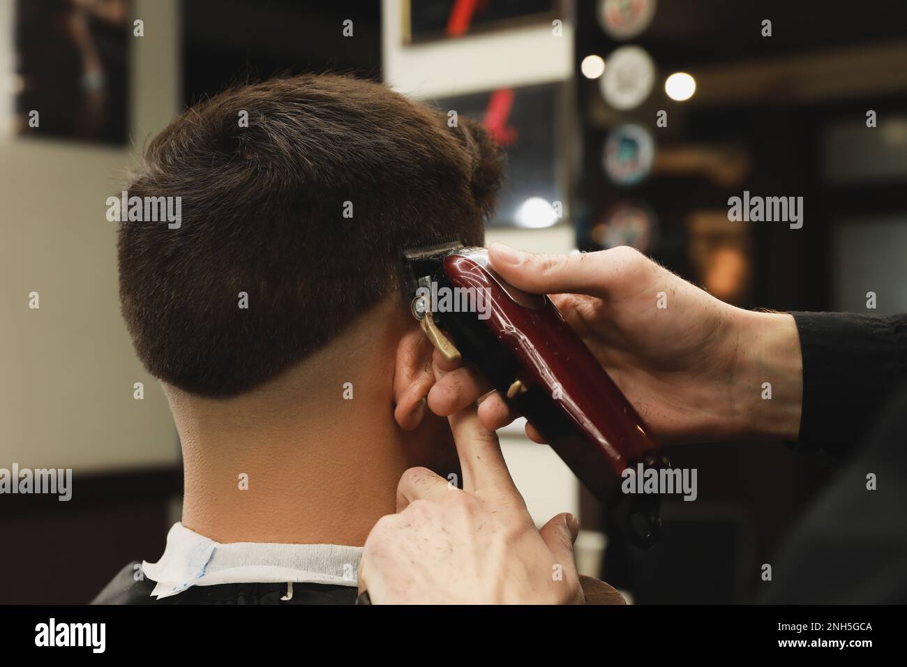 Professional hairdresser making stylish haircut in salon, back view