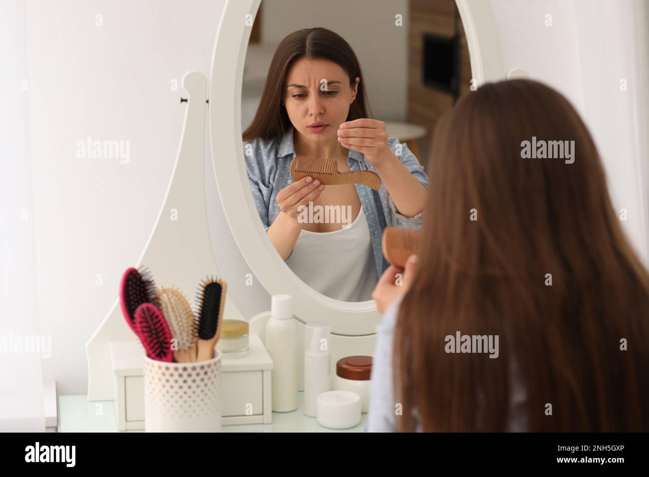 Emotional woman with hair loss problem near mirror indoors Stock Photo