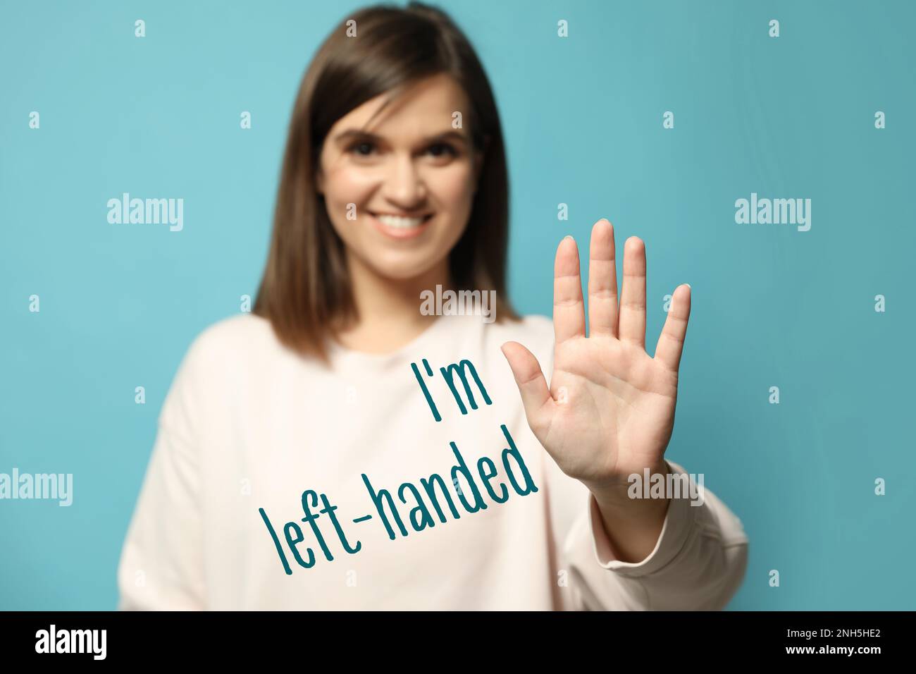 Lefthanded woman against light blue background, focus on palm Stock