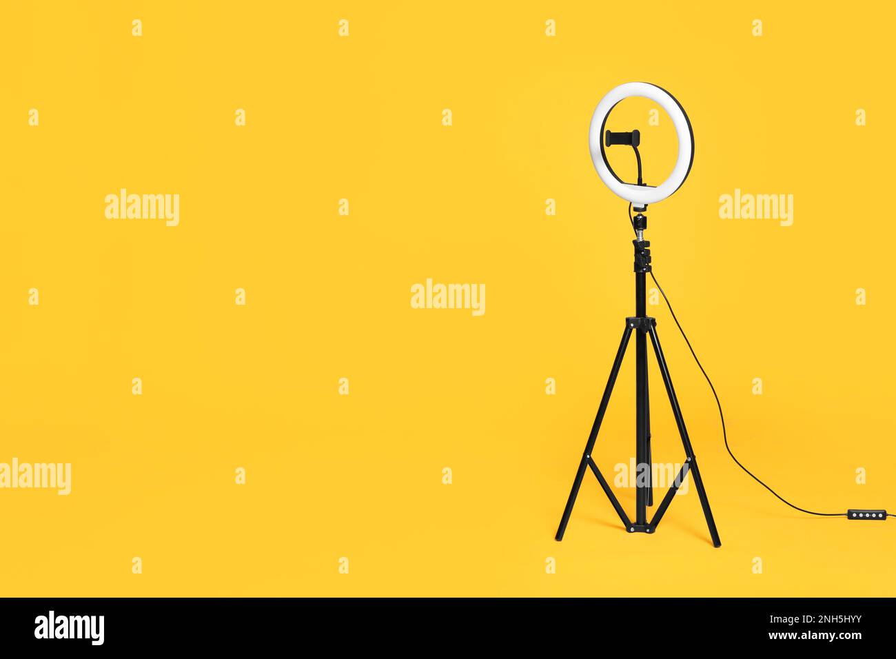 Modern tripod with ring light on yellow background. Space for text ...