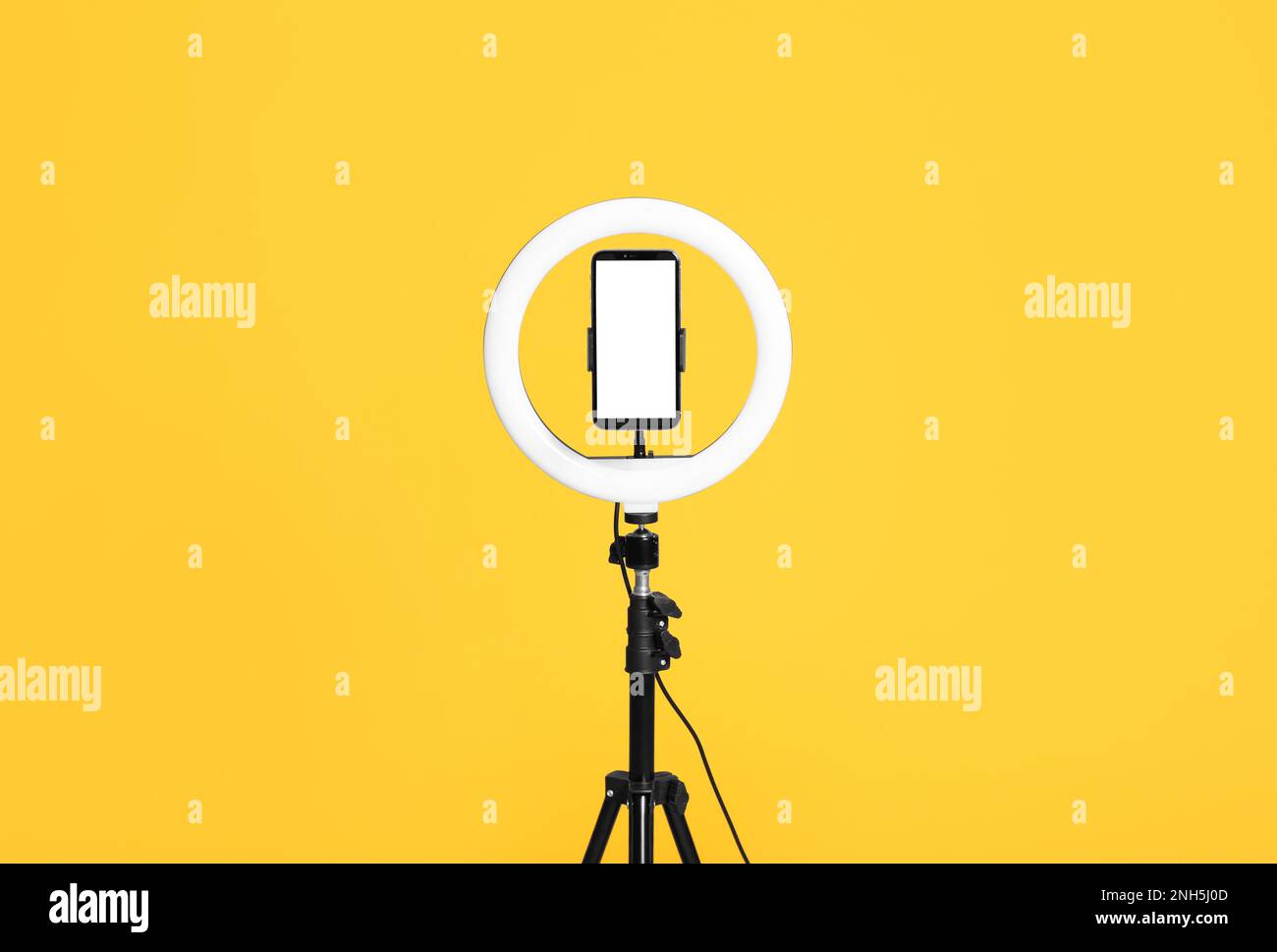 Modern tripod with ring light and smartphone on yellow background Stock ...