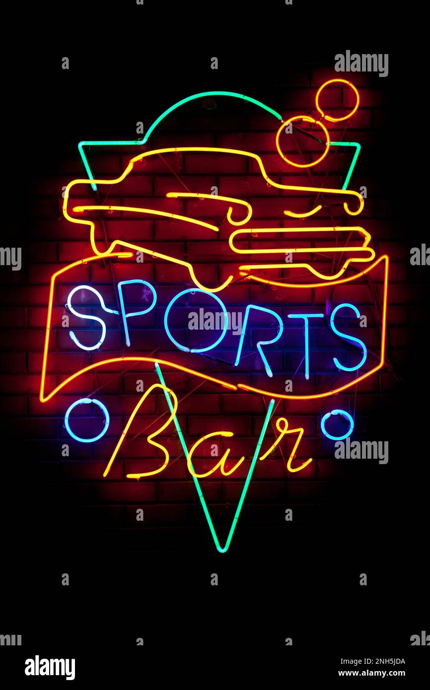 Retro neon light saying 'Sports bar' bellow a classic car. Stock Photo