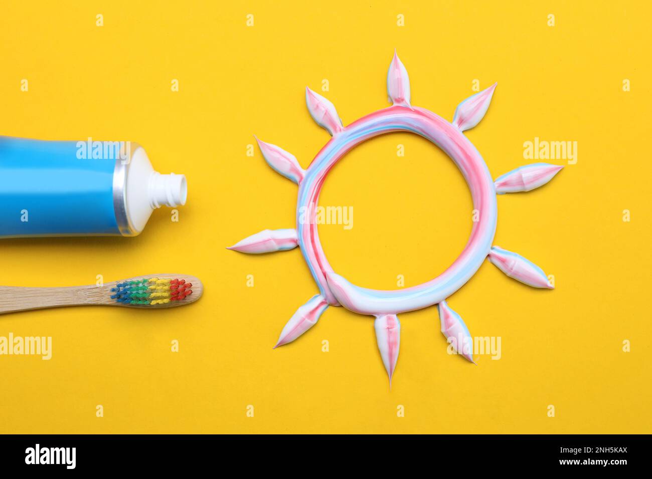 Sun made with toothpaste, brush and tube on yellow background, flat lay ...
