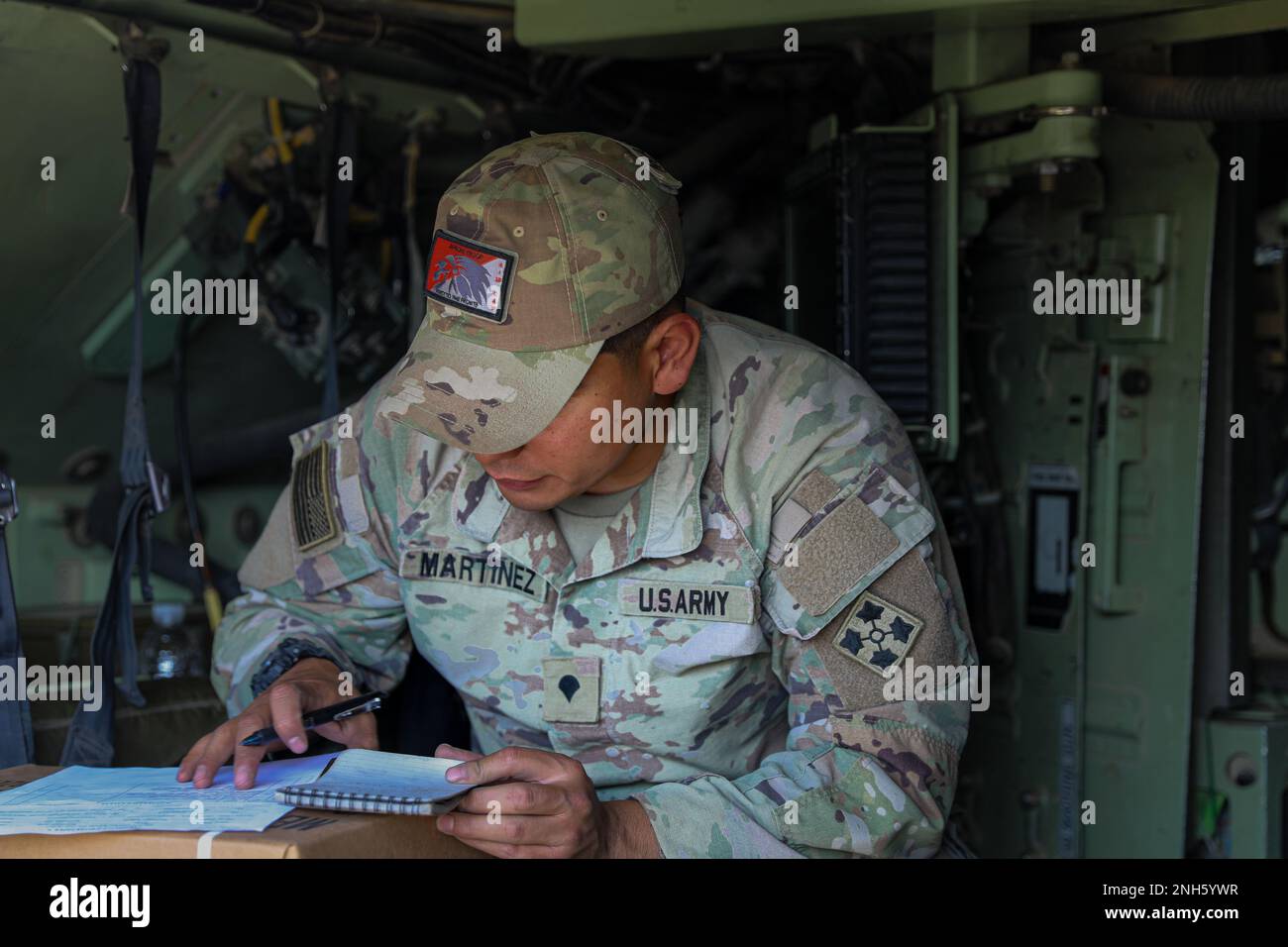U.S. Army Spc. Mario Martinez Jr., assigned to Apache Troop, 4th Squadron, 10th Cavalry Regiment, 3rd Armored Brigade Combat Team, 4th Infantry Division, takes notes as he conducts a gunnery skills test certification at Trzebień, Poland, July 18, 2022. The 3/4 ABCT is among other units assigned to the 1st Infantry Division, proudly working alongside NATO allies and regional security partners to provide combat-credible forces to V Corps, America's forward-deployed corps in Europe. Stock Photo