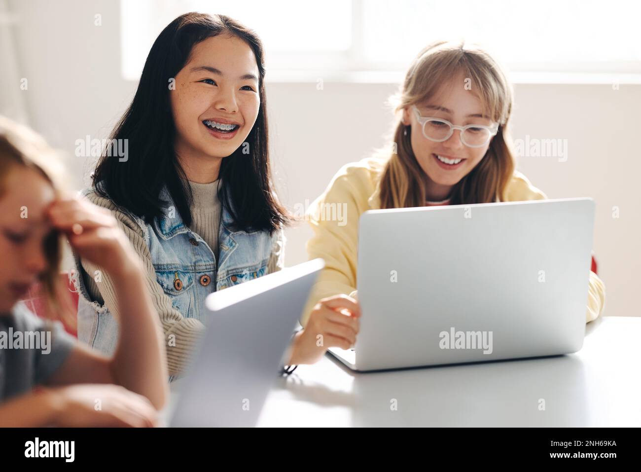 Female students sitting at their desk with smiles on their faces as they engage in a coding lesson. Kids attending school in an environment that focus Stock Photo