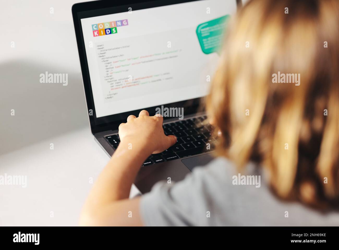 Young elementary school child programming on a laptop in a classroom. Smart little kid developing his digital literacy and coding skills by performing Stock Photo