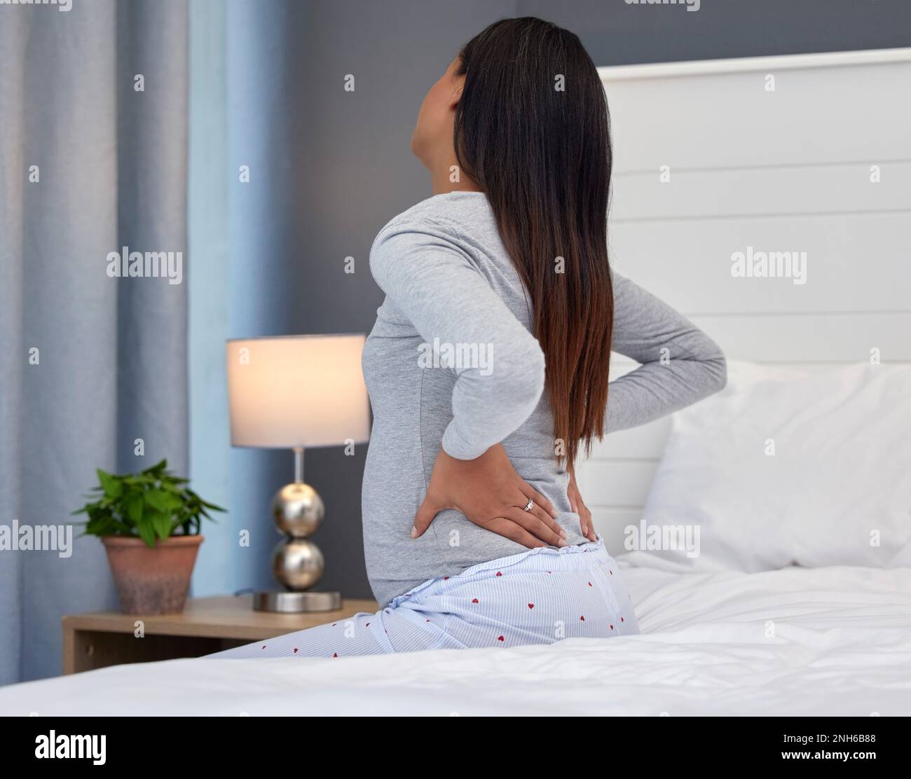 Tired, burnout and pregnant woman with back pain on a bed for rest, injury and fatigue