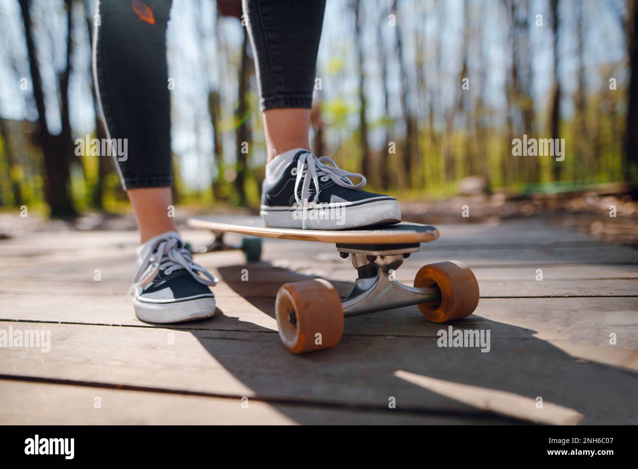 Cropped view of the skater girl in forest. Female teenager in casual outfit  standing on skateboard. Summer skateboarding with modern sport equipment a  Stock Photo - Alamy