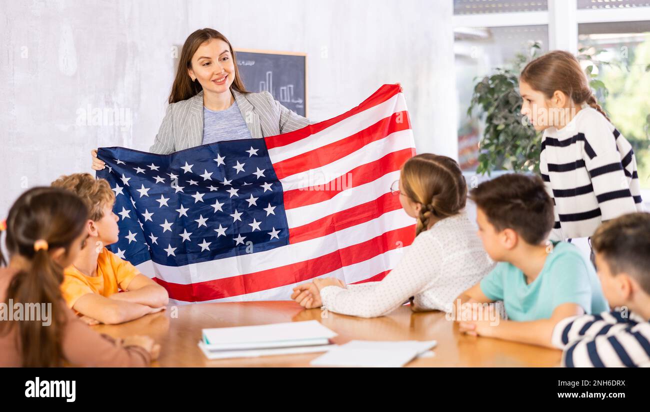 Geography lesson in school class - teacher talks about United States of America, holding flag in his hands Stock Photo